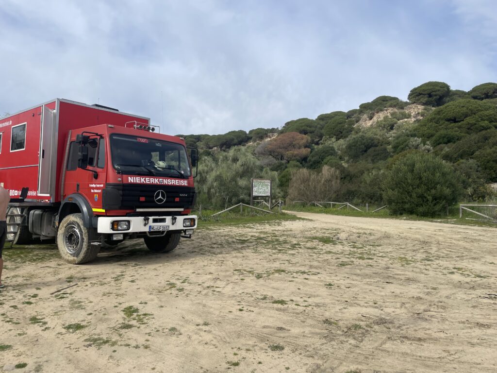 Zum Wohnmobil umgebauter Feuerwehr LKW auf einem Parkplatz am Strand in Barbate