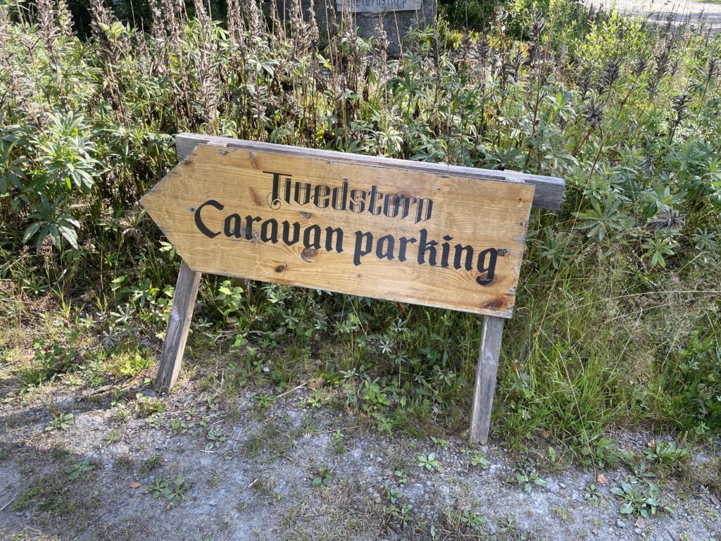 Holzschild mit der Aufschrift ‚Tivedstorp Caravan Parking‘ am Wegesrand im Tiveden Nationalpark.