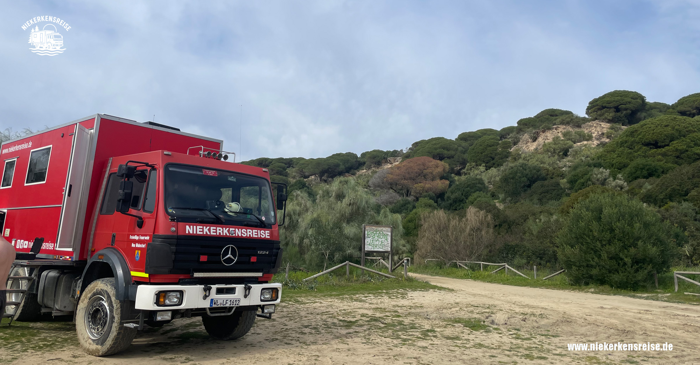 Freier Stellplatz bei Barbate mit rotem Expeditionsmobil vor grüner Hügellandschaft