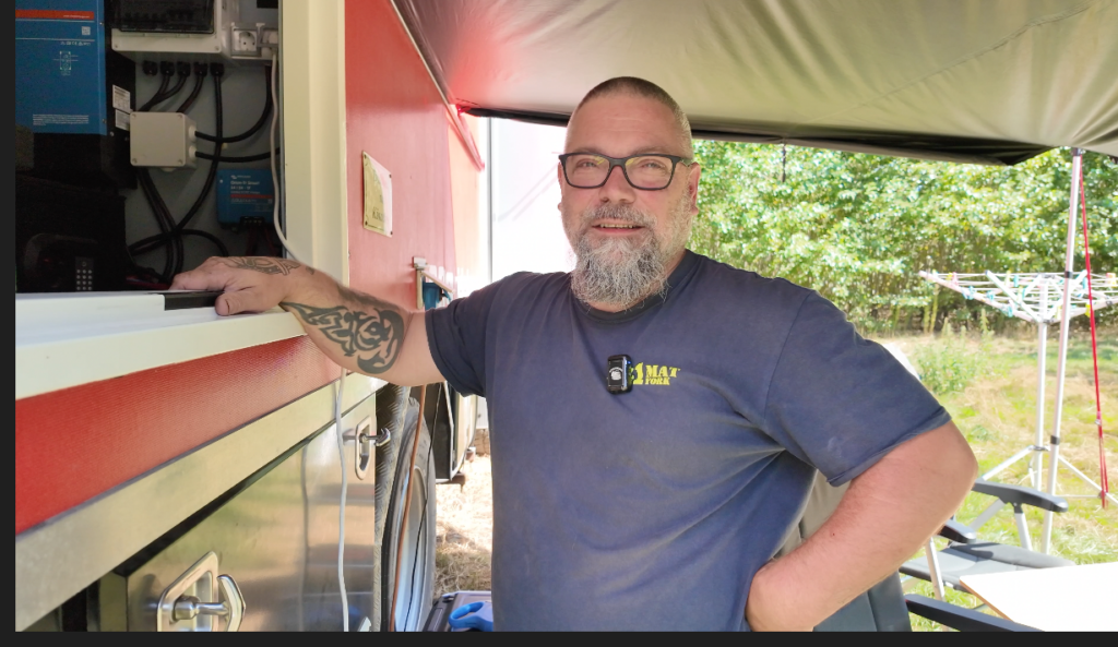 Lars steht neben der Elektroinstallation im Feuerwehr-LKW und erklärt das Strom-Setup mit Victron-Komponenten.