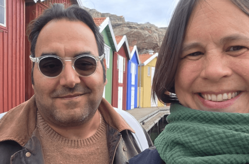 Betty und Florian vom Wohnmobil-YouTube-Kanal Außer Haus auf Reisen vor bunten Holzhäusern in Schweden.