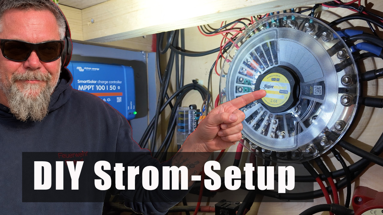 DIY Stromsetup Lars zeigt auf die Elektrik des DIY Strom-Setups im Feuerwehr-LKW mit Victron Solarladeregler und Stromverteilung.