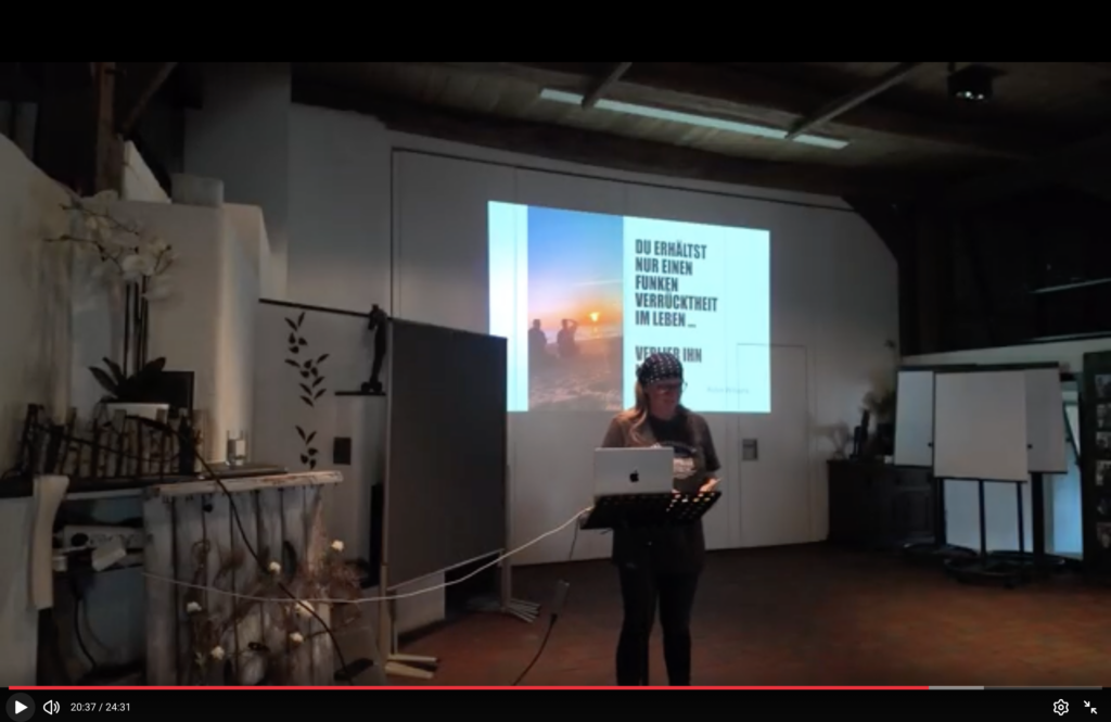 Autorin Anja Niekerken bei ihrem Lesevortrag aus dem Buch „Kein Reisebuch“ auf dem Hof & Hubraum Treffen 2026. Sie steht mit Laptop am Rednerpult, während im Hintergrund eine Präsentation über das Leben und persönliche Entscheidungen zu sehen ist.