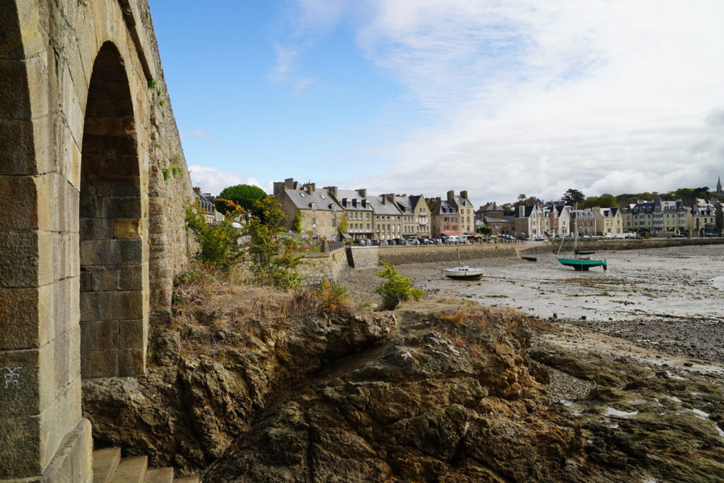 Blick auf den Hafen von Saint-Servan in Saint-Malo, Bretagne, bei Ebbe. Segelboote liegen auf dem trockengefallenen Meeresboden vor historischen Häusern und einer Kirche.