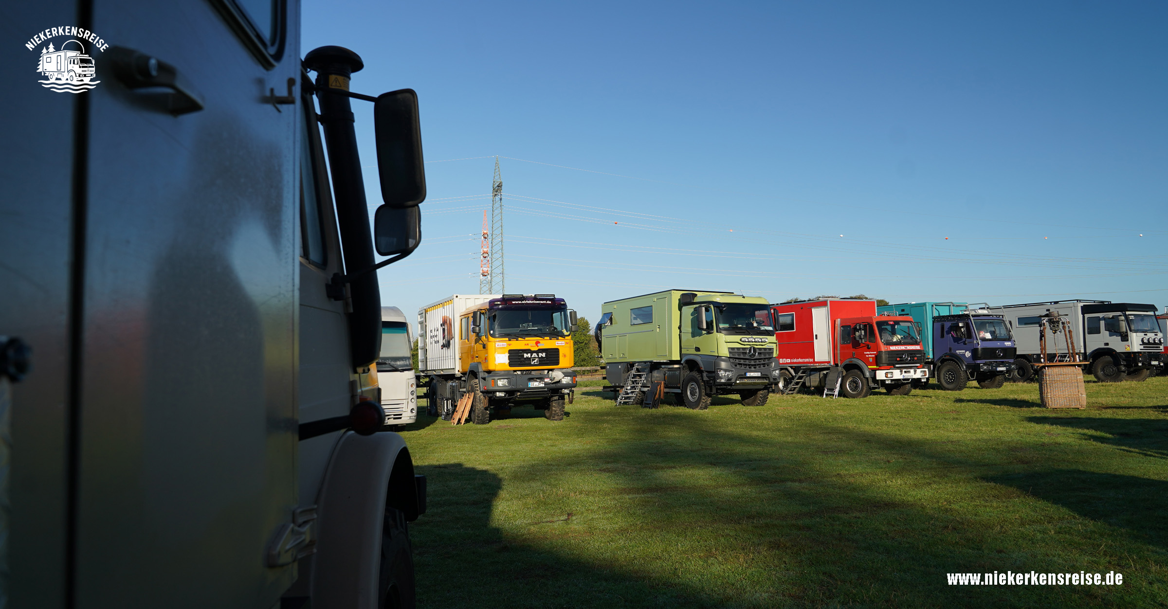 Expeditionsmobile und Allrad-LKW beim Hof & Hubraum Treffen 2026 auf einer grünen Wiese. Zu sehen sind mehrere individuell ausgebaute Wohn-LKW, darunter Fahrzeuge von MAN und Mercedes-Benz.