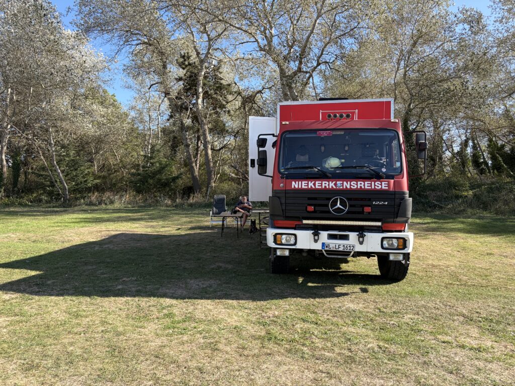 Unser Mercedes-Benz 1224 4x4 auf einem grünen Campingplatz während der vierwöchigen Wohnmobilreise durch Frankreich.