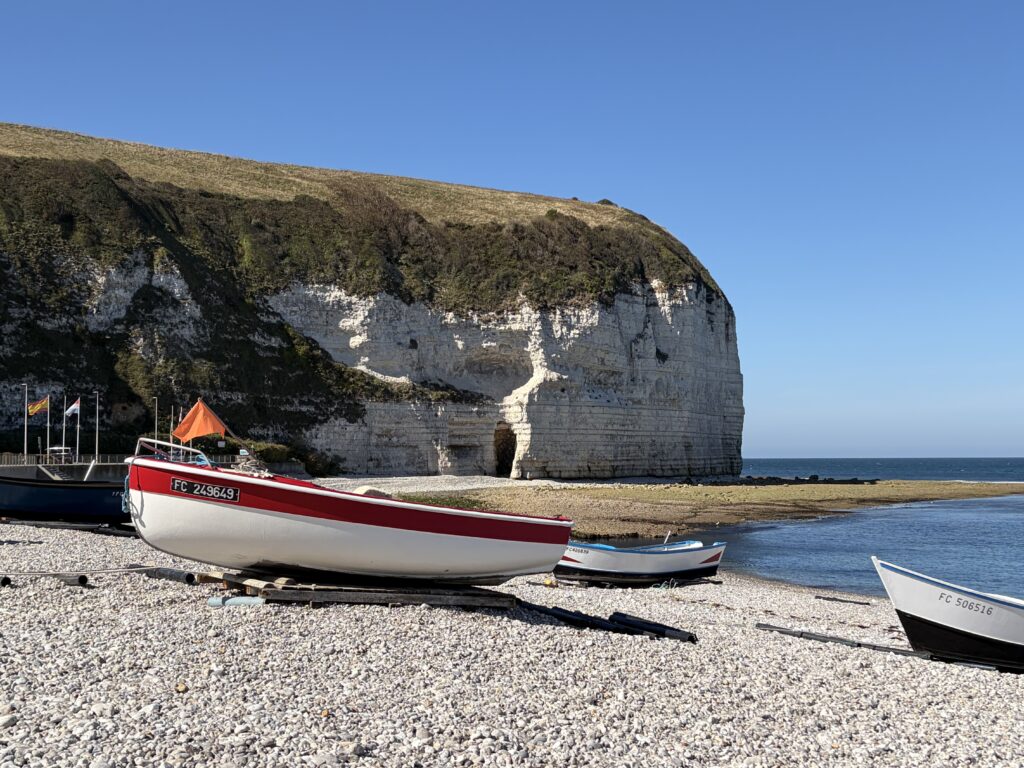 Fischerboote am Kiesstrand von Yport vor den weißen Kreidefelsen der Alabasterküste in der Normandie.