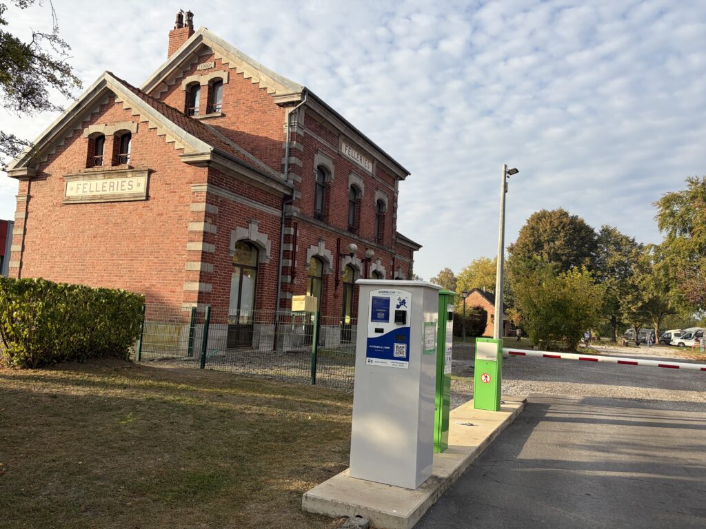 Einfahrt zum Camping-Car-Park-Wohnmobilstellplatz in Felleries mit Zugangsterminal vor dem historischen Bahnhofsgebäude.