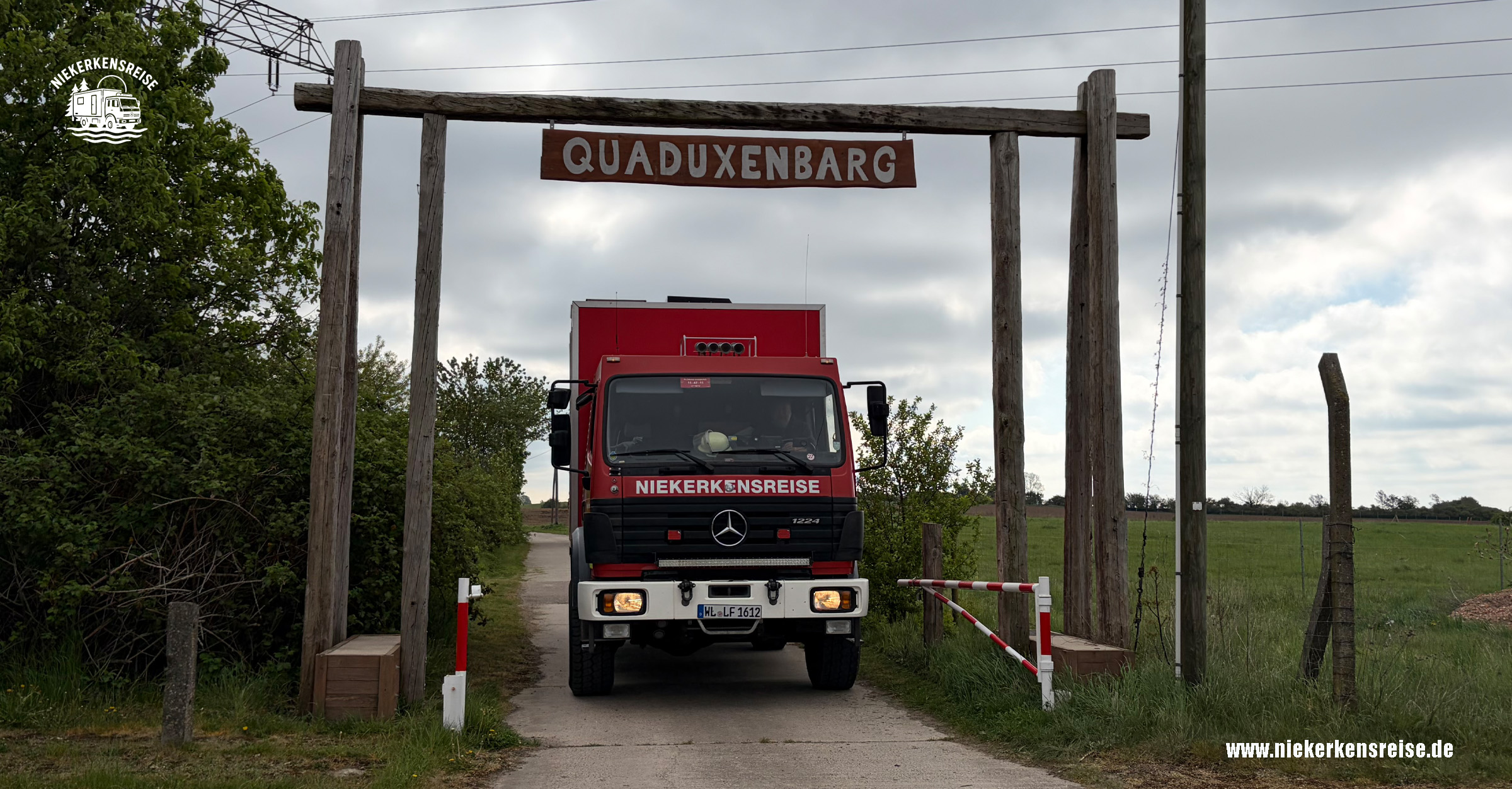 Overlander-Treffen Quaduxenbarg 2026 – Niekerkensreise mit dem Expeditions-LKW Roter Mercedes-Benz 1224 AF Expeditions-LKW von Niekerkensreise bei der Einfahrt zum Overlander-Treffen Quaduxenbarg vom 1. bis 3. Mai 2026 unter dem hölzernen Eingangstor.